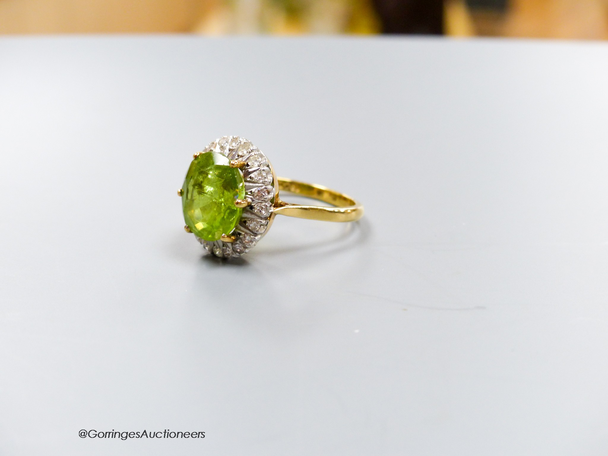 An 18ct, peridot and diamond oval cluster set dress ring, size T, gross 7 grams.